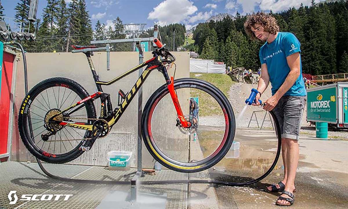 Un uomo pulisce la propria mountainbike con l'idropulitrice