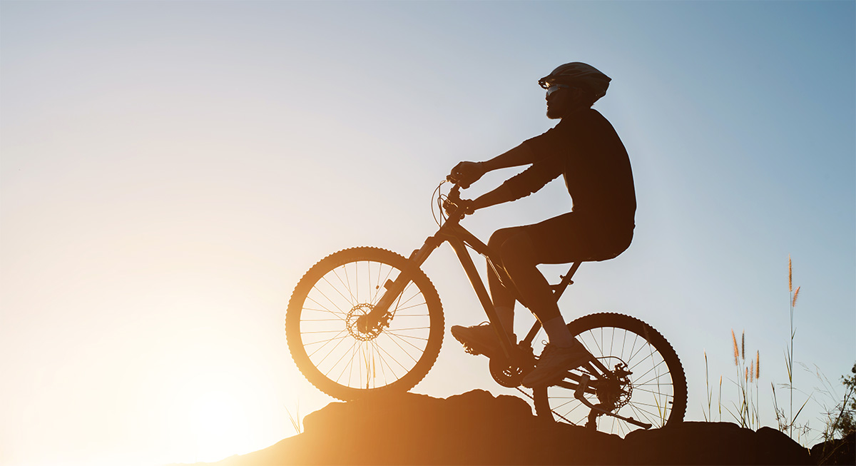 Un rider in sella alla propria mountainbike al tramonto