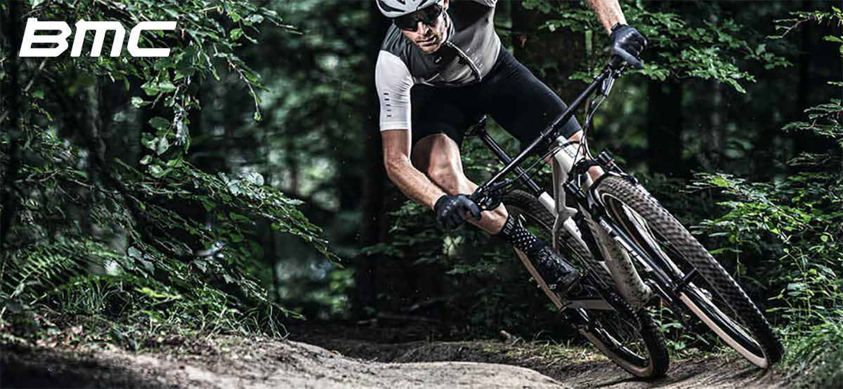 Un rider pedala su un percorso nel bosco in sella di una nuova mtb BMC Twostroke 2022